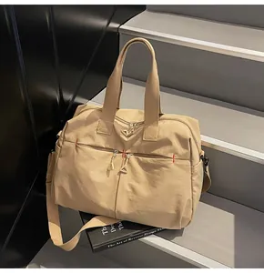 Dettaglio borsa da viaggio in tela kaki con cuciture rosse e cerniere metalliche robuste