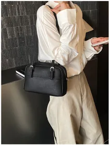 Detailed view of black litchi texture shoulder bag with silver buckle on a model