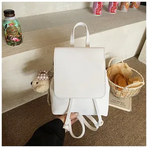 Detail of white PU leather mini backpack with cute teddy bear charm on side step