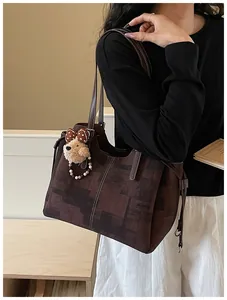 Détail d'un grand sac cabas marron à imprimé géométrique avec un charmant ours peluche