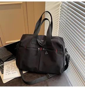 Dettaglio borsa da viaggio nera con doppie tasche a zip e cuciture rosse a contrasto