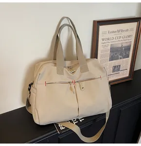 Dettaglio della borsa da viaggio in tela beige con tasche anteriori e manici robusti