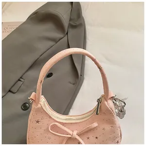 Detail van de roze maanvormige tas met sterpatronen en een verfijnde strik aan de voorkant