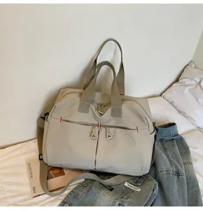 Dettaglio borsa da viaggio in tela grigia con cuciture rosse e zip triangolari
