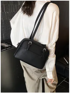 Close-up of black lychee grain leather handbag with adjustable silver metal buckle