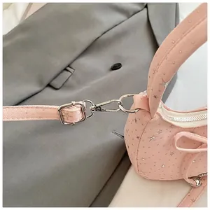 Detail van roze tas met sterpatroon, zilveren metalen gespen en decoratieve strik