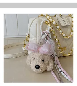 Dettaglio di ciondolo a cucciolo di peluche con fiocchi rosa su borsa trapuntata