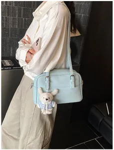 Detail view of light blue lychee pattern crossbody bag with a cute white rabbit pendant