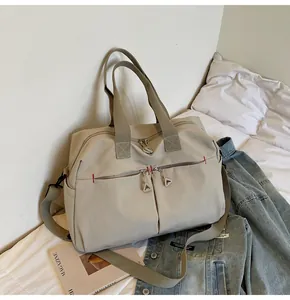 Dettaglio della borsa da viaggio in tela con tasche a zip e cuciture rosse a contrasto