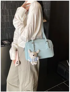 Detail of light blue lychee pattern crossbody bag with a cute white bunny pendant