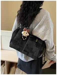 Détail du grand cabas noir texturé avec coutures blanches et charm d'ours en peluche