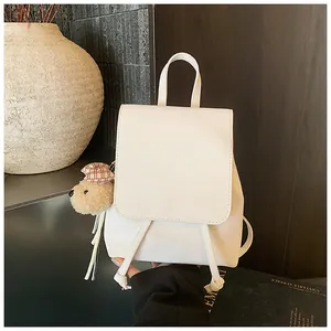Detailed side view of a white PU leather backpack featuring a cute brown plush bear charm
