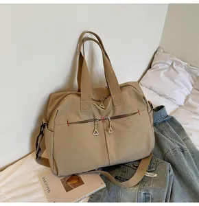 Dettaglio della borsa da viaggio in tela kaki con tasche a zip e cuciture rosse a contrasto