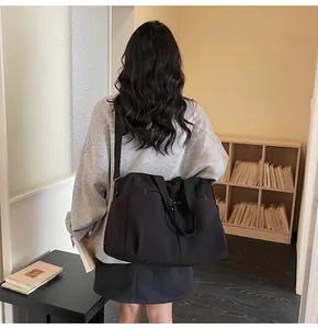 Vista posteriore di una borsa da viaggio nera capiente in tela con tracolla regolabile