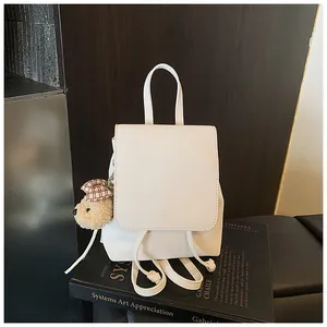 Close-up of a white mini backpack with a drawstring flap and a cute teddy bear charm