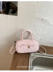 Close-up of pink polka dot handbag featuring a floral bow and gold heart pendant detail