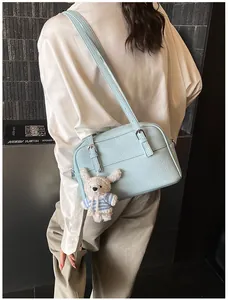 Detail of light blue pebble leather crossbody bag with a cute white bunny charm