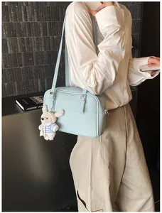 Close-up of light blue lychee pattern crossbody bag with a cute plush rabbit pendant