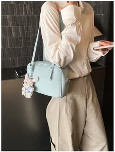 Detail of light blue lychee pattern crossbody bag with a cute white bunny plush pendant