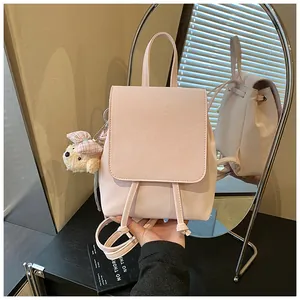 Detail of pink PU backpack showing drawstring closure and cute plush bear charm