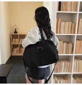 Dettaglio della borsa da viaggio nera con cuciture rosse e tracolla in uno studio