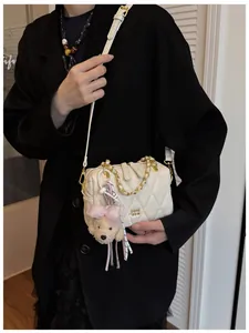 Borsa a tracolla beige trapuntata con catena dorata e ciondolo a forma di cucciolo