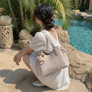 Sac cabas beige texturé avec charm ours mignon présenté dans un cadre extérieur
