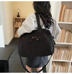 Vista posteriore di una borsa da viaggio in nylon nero con cuciture rosse e tracolla