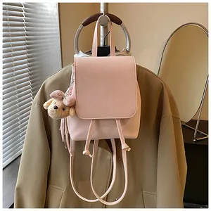 Detail of light pink PU leather backpack with drawstring closure and plush dog pendant