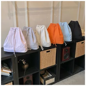 Minimalist canvas drawstring bucket bags in multiple colors displayed on a modern black rack