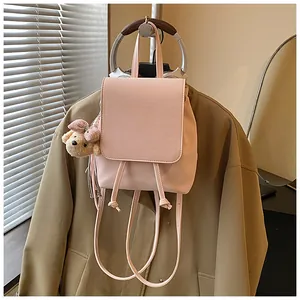 Detail of pink PU leather backpack with drawstring closure and cute plush bear charm