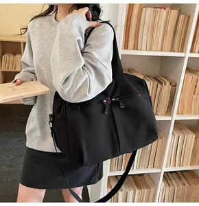 Dettaglio borsa da viaggio nera con doppia zip, cuciture rosse e tracolla regolabile