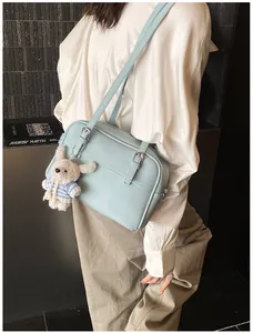 Detail of light blue lychee pattern crossbody bag with silver buckle and plush rabbit charm