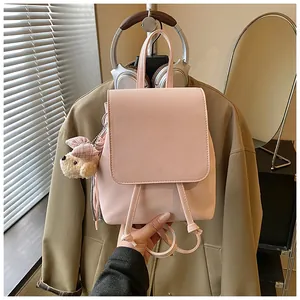 Detail of pink faux leather mini backpack with cute bow charm in a cozy indoor scene
