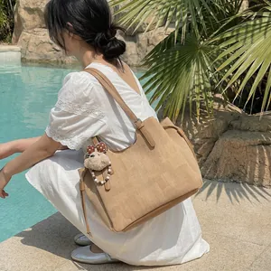 Sac cabas chic en velours côtelé kaki avec pendentif ours dans un décor de vacances