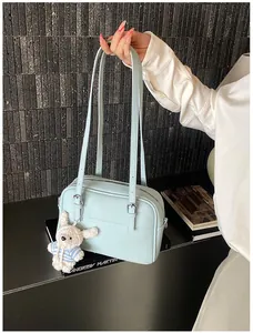Detail of light blue lychee texture leather bag featuring a cute bunny plush charm