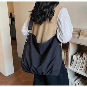 Detail van de grote zwarte canvas hobo-tas met zilveren klinknagels en brede schouderriem