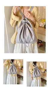 Detail of grey canvas drawstring backpack showing shoulder straps and cinch closure