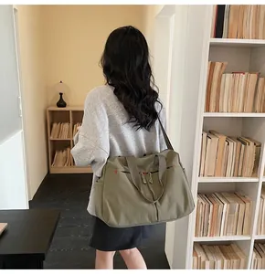 Dettaglio della grande borsa da viaggio in tela verde oliva con cuciture rosse e doppi manici