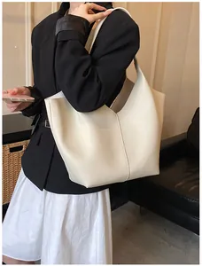 Close-up of cream-colored pebble leather tote bag with V-cut opening on model