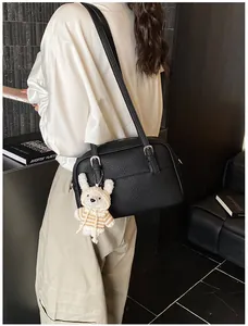 Detail of black lychee grain crossbody bag with a cute white bunny pendant charm