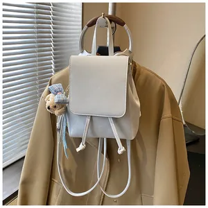 Detailed shot of white PU leather backpack with a cute teddy bear charm and drawstring top