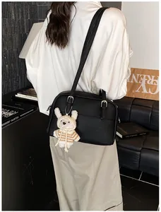 Close-up of black lychee grain leather crossbody bag with a cute white plush bear pendant