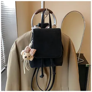 Detailed view of black flap backpack with drawstring and cute bear charm in a daily setting