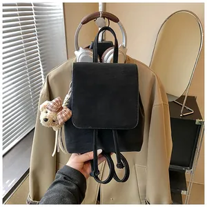 Detail of black matte drawstring backpack with a cute plush bear pendant and flap design