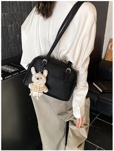 Detail of lychee textured leather crossbody bag with a cute plush bunny charm
