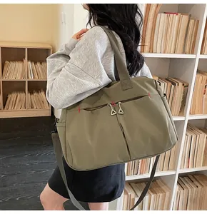 Dettaglio della borsa in tela verde oliva con cuciture rosse rinforzate e tasca con zip