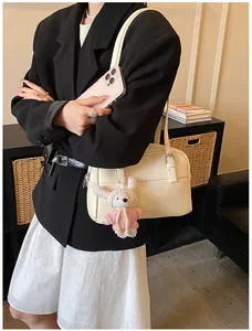 Close-up of beige lychee texture leather bag featuring a cute white rabbit plush charm