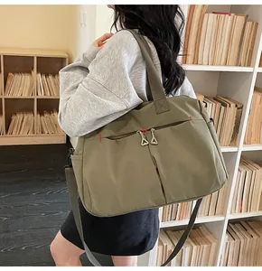 Dettaglio della borsa da viaggio in tela verde oliva con tasche a zip e tracolla larga
