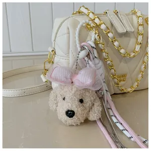 Dettaglio di ciondolo a forma di cane in peluche su borsa a catena trapuntata bianca